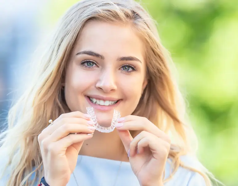 Teen girl smiling holding Invisalign retainer